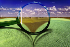 Magnifying class in front of wind turbine field with book under it.
